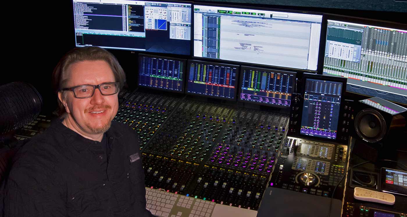 Charles Deenen sat in front of film mixing console in post production studio