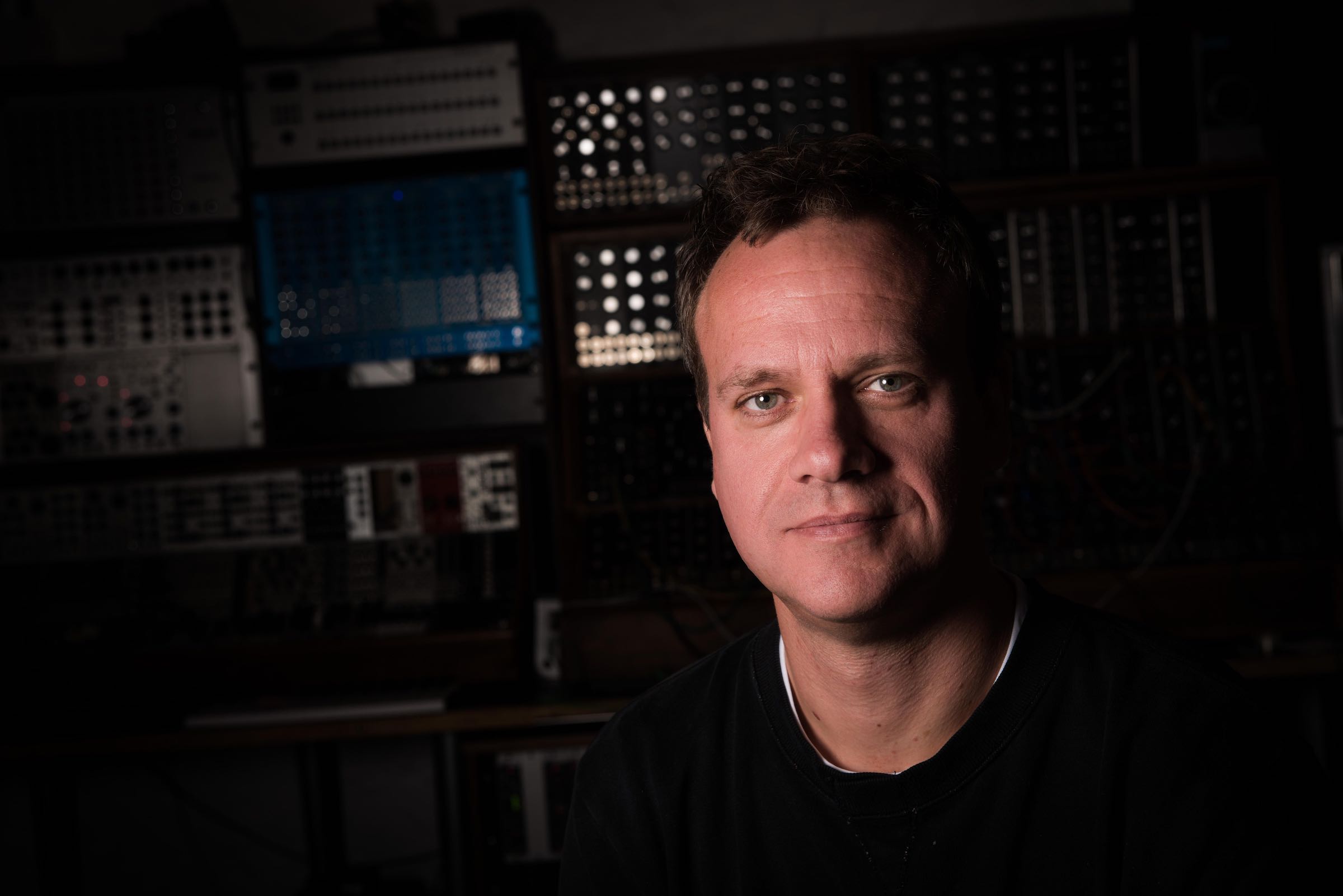 Dom Morley in front of a wall of modular synths