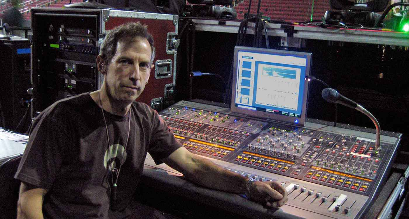 Michael Prowda sat at live sound console in a stadium before a gig