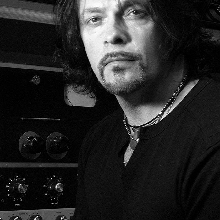 Richard Chycki stodd in front of analogue hardware in black and white